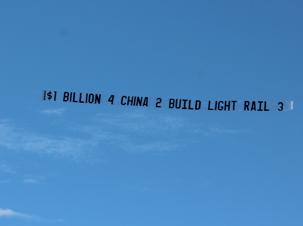 Banner in the sky reads "$1 Billion 4 China 2 Build Light rail 3"