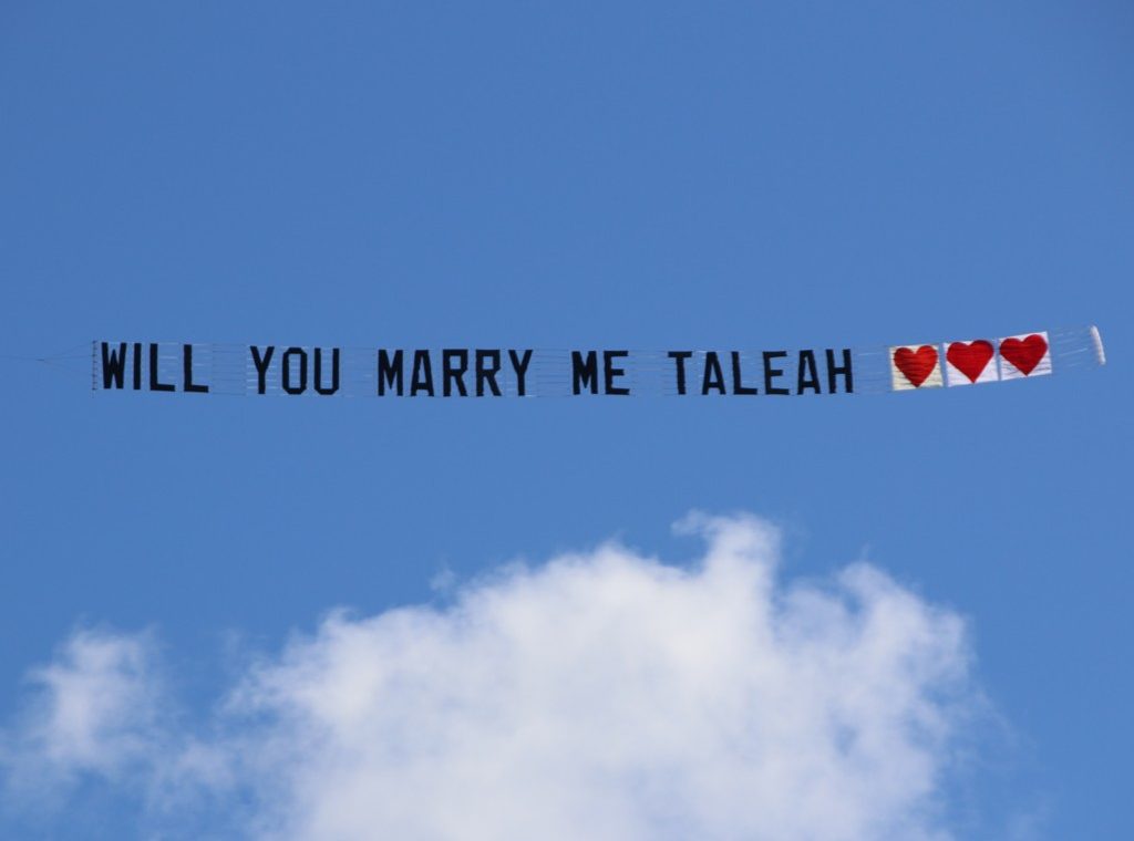Aeroplane Sign reads "Will You Marry Me Taleah" Followed by 3 Red Love Hearts